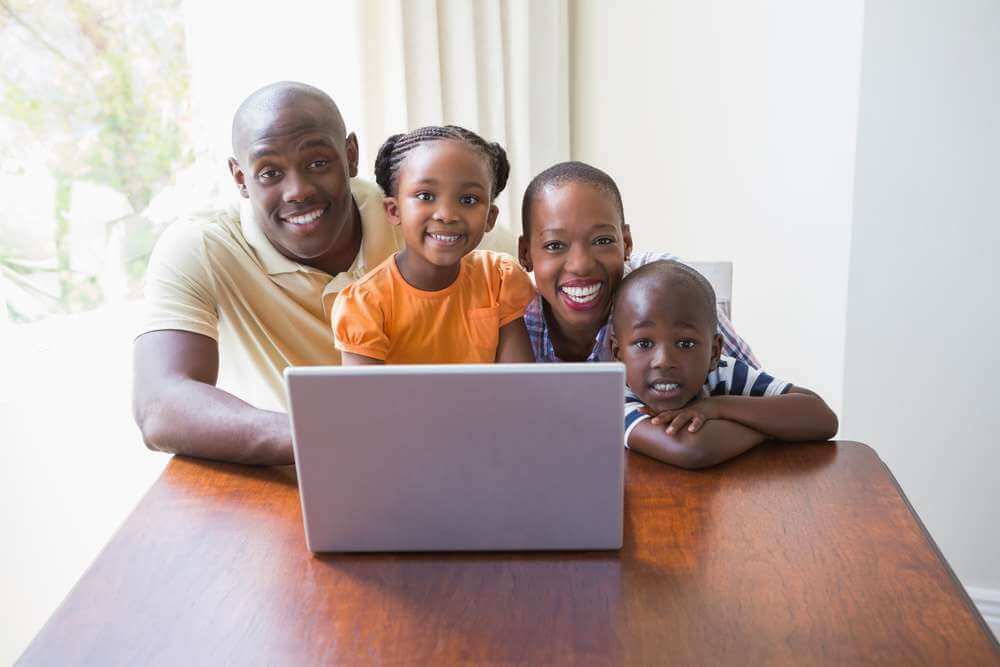 Happy smiling family using laptop at home